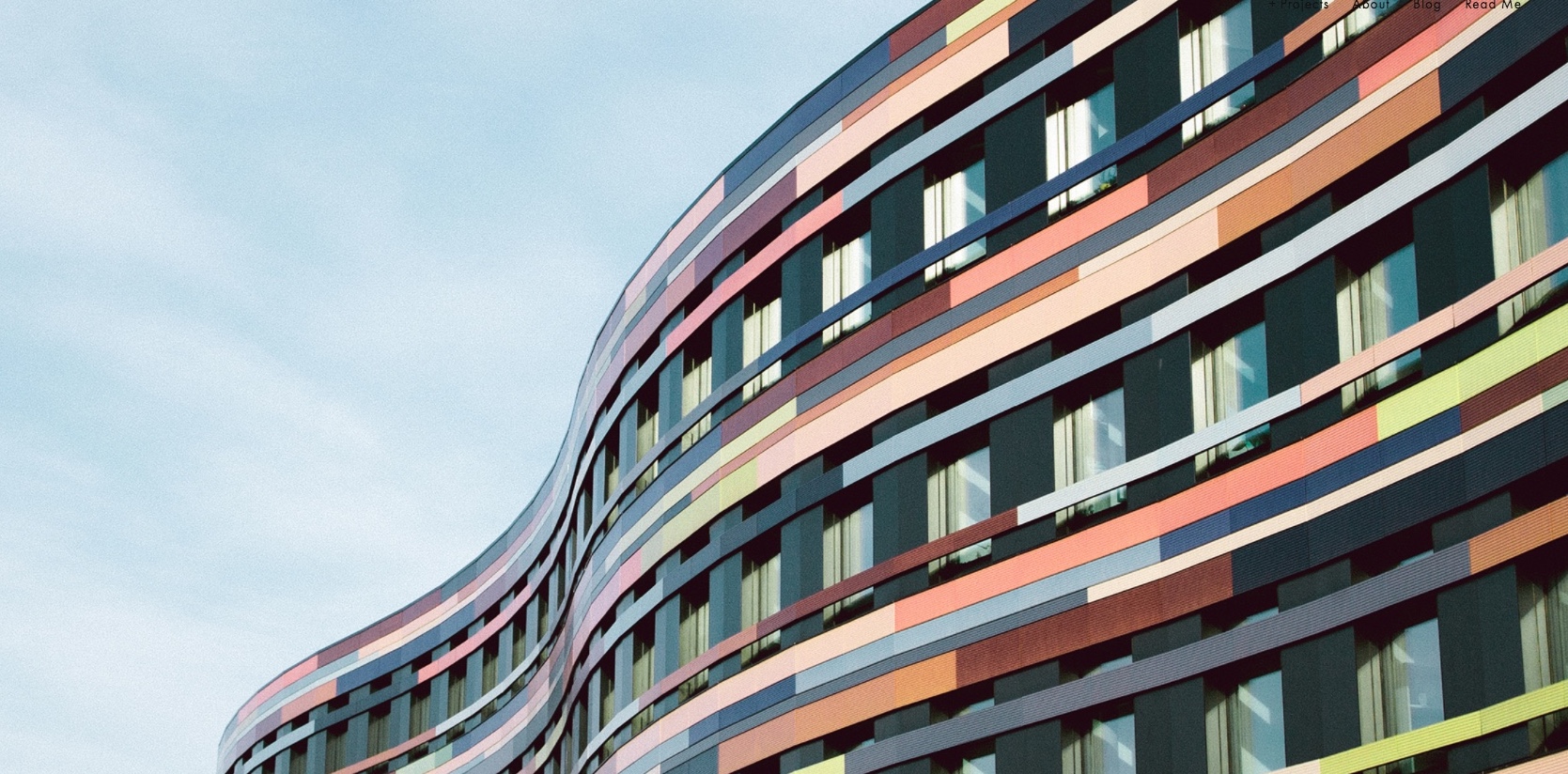 A modern building with a wave-like structure features colorful horizontal stripes in shades of red, pink, orange, and brown. Large, evenly spaced windows create a rhythmic pattern against a clear blue sky, while innovative access control in office automation ensures seamless security.