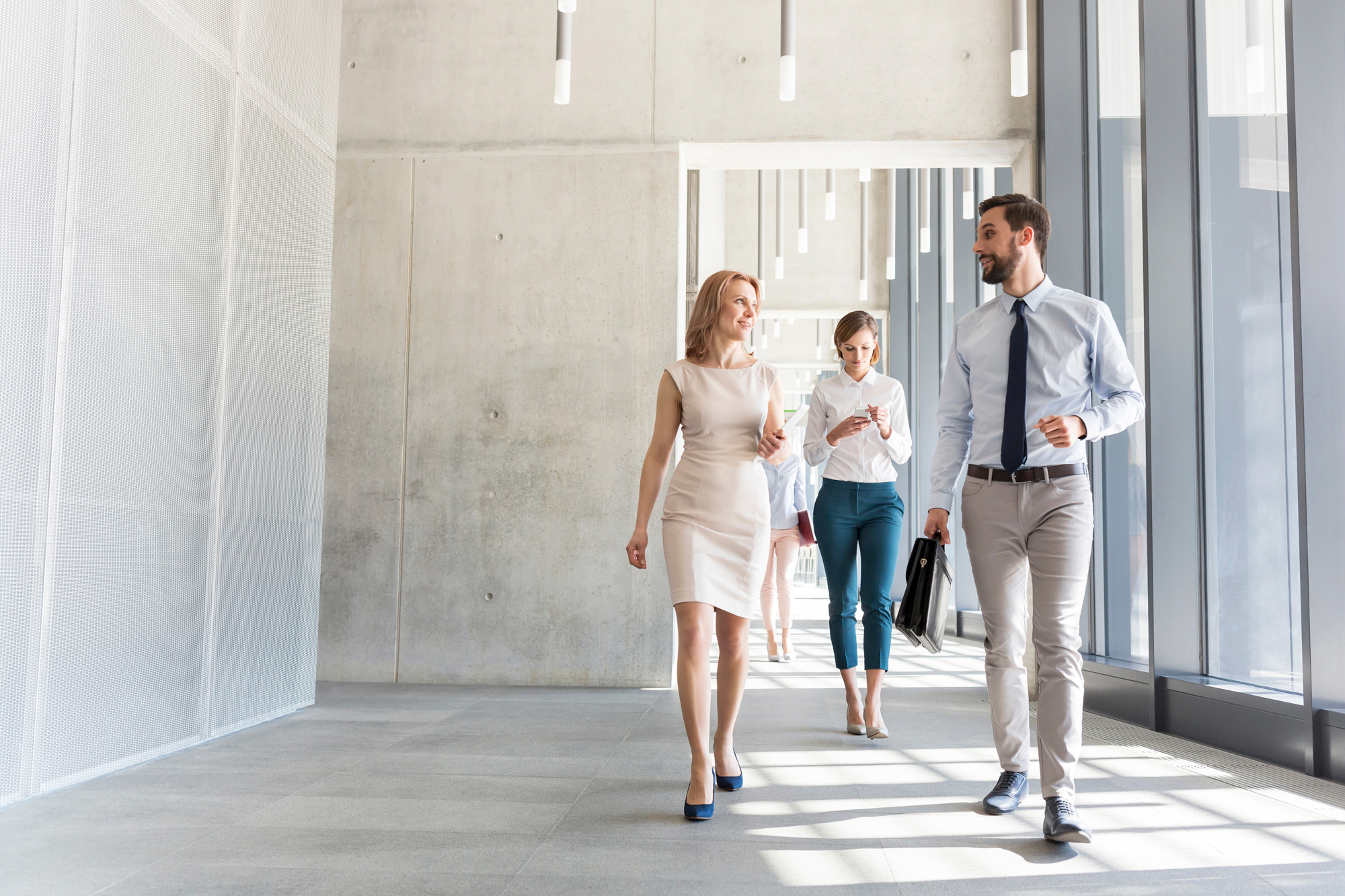 3 people walking down hallway of building