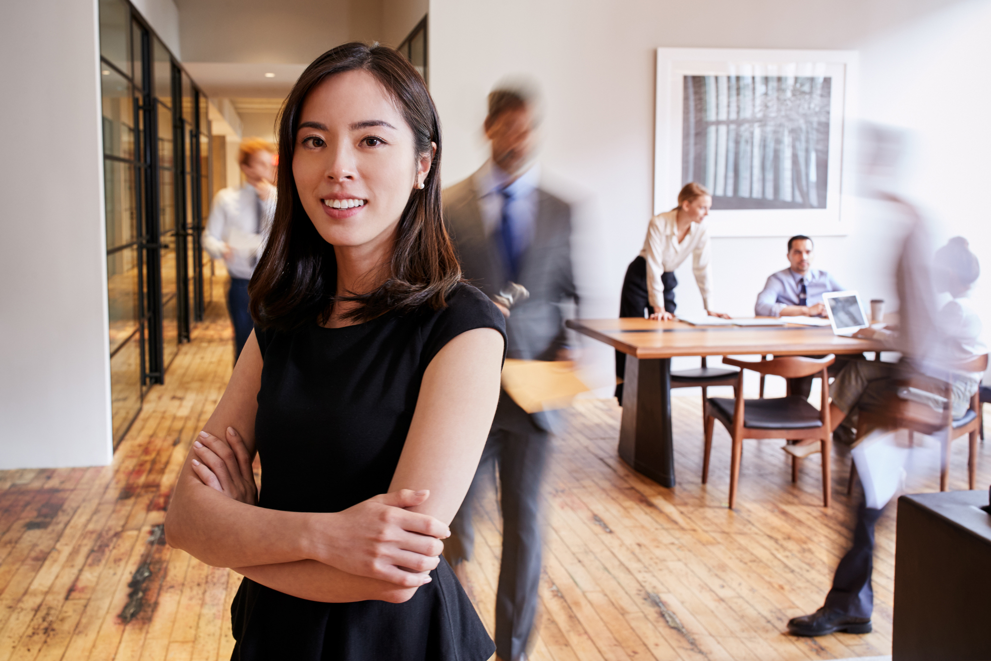 woman with arms crossed in front of busy office