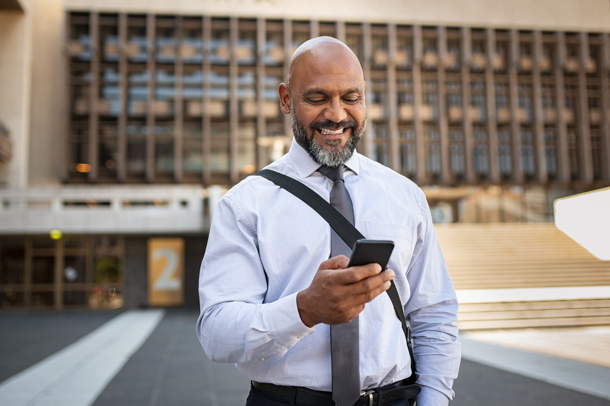 man on side of street smiling at phone